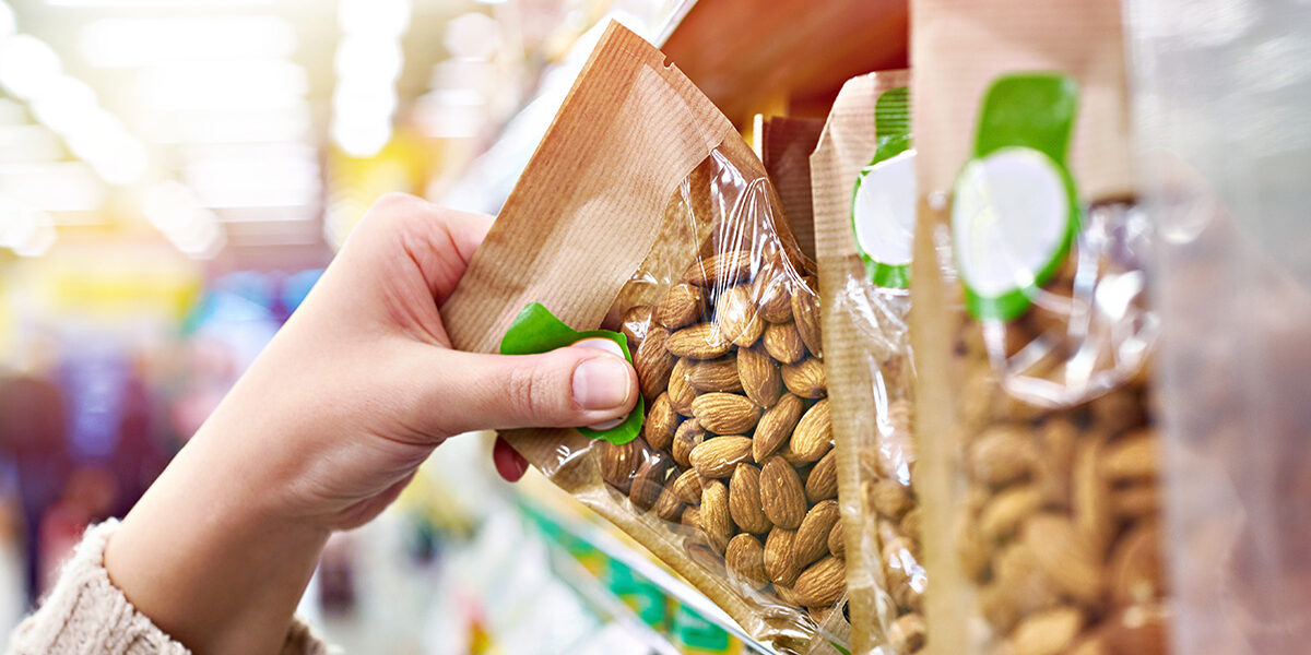 Hand with packaging of almond nuts in store Purchasing a package of almonds in a micro Store